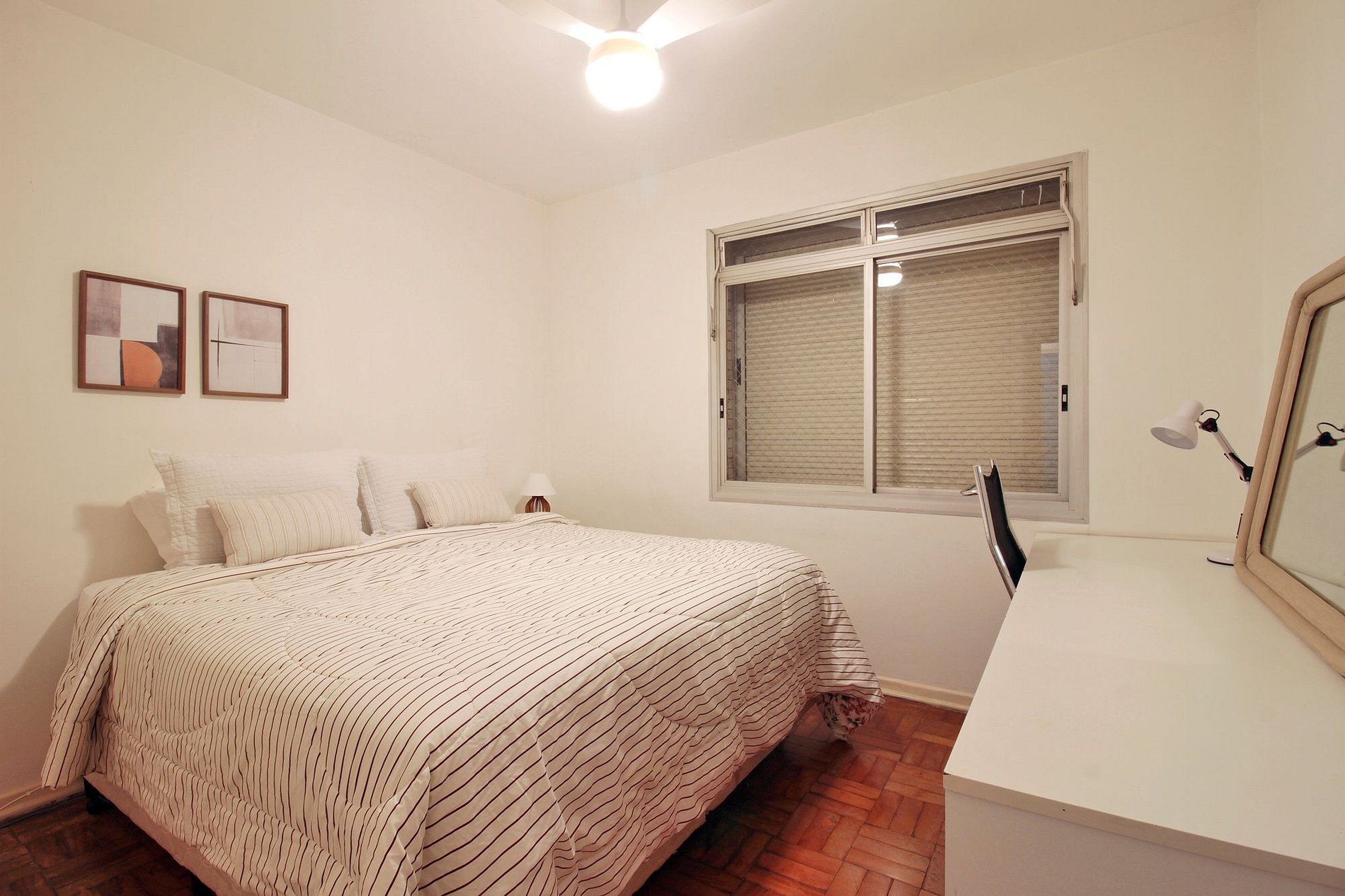 Quarto principal mobiliado, com cama king, bancada e piso de madeira