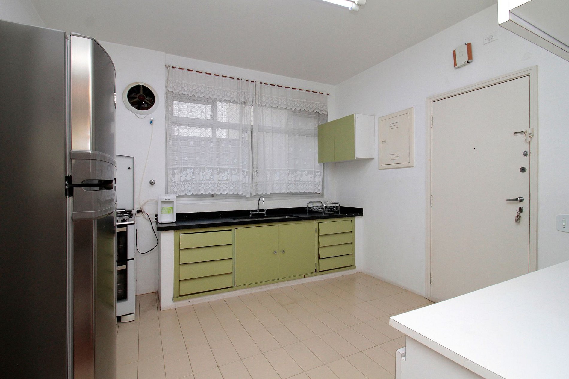Cozinha com geladeira, fogão, bancada e armários